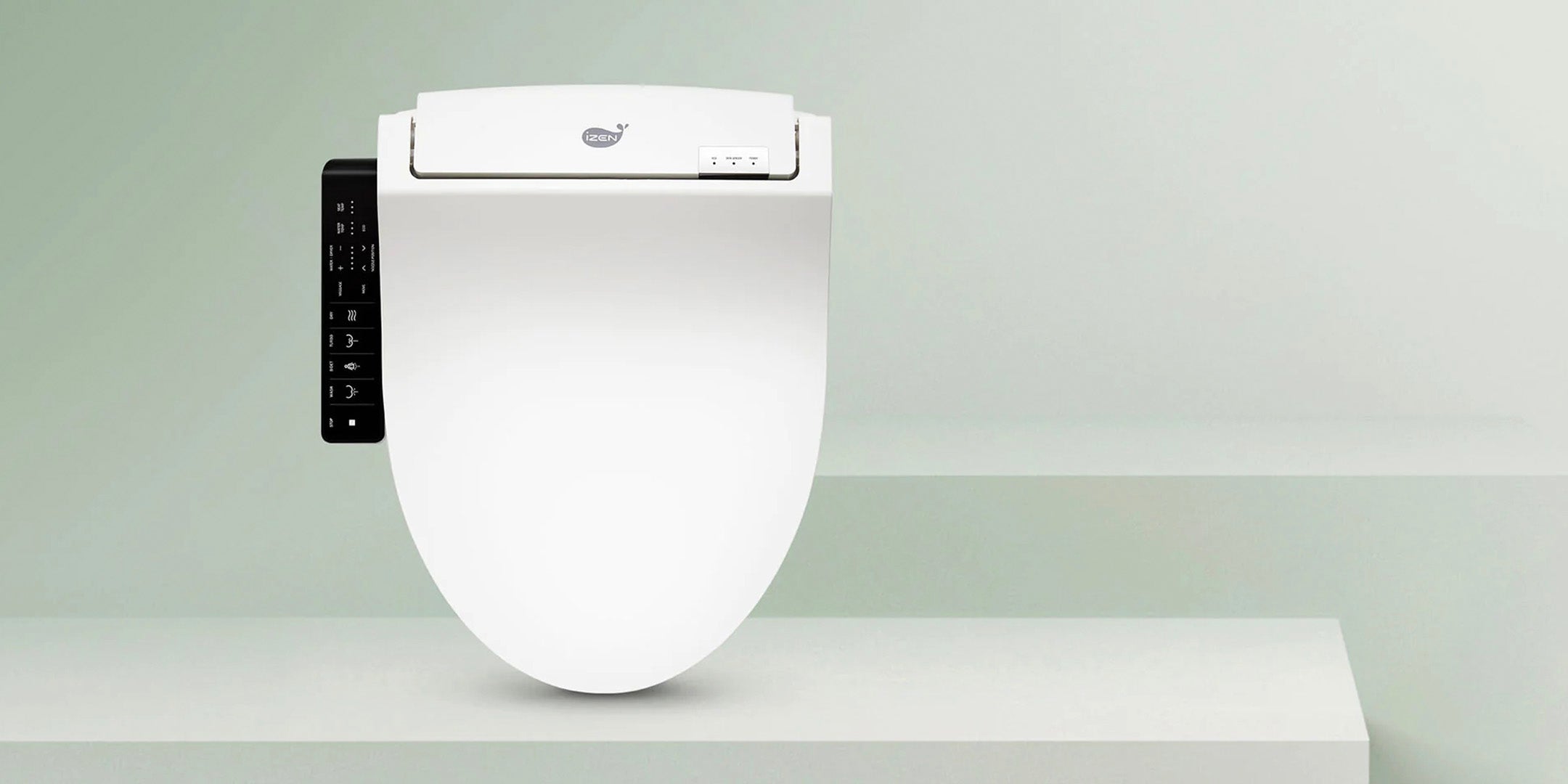 White IZEN bidet seat with side controls against a pale green studio backdrop